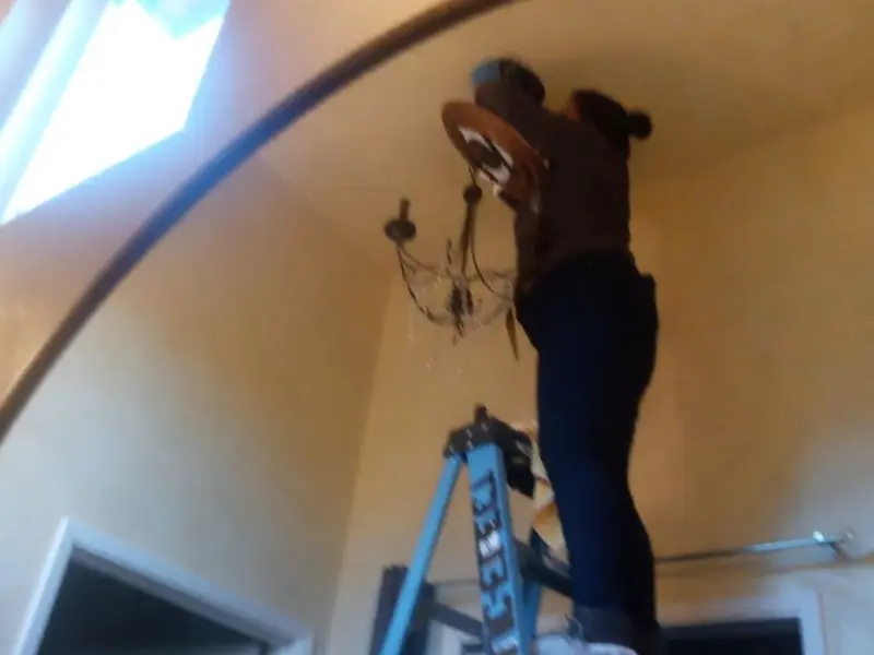 Electrician installing a chandelier in a Bixby residence